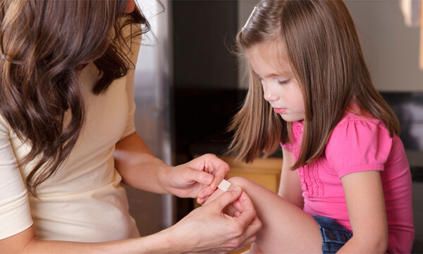 A photo of a young girl having a plaster applied to her knee