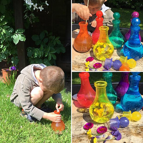 A child putting petals, rocks and flowers into multi-coloured translucent bottles that look like they should have potions in