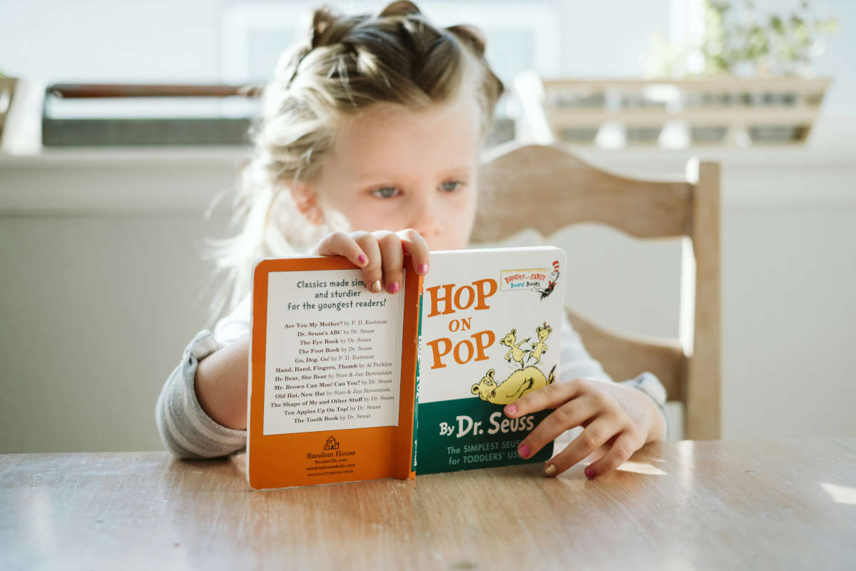 A child sat at a table with a Dr. Seuss book