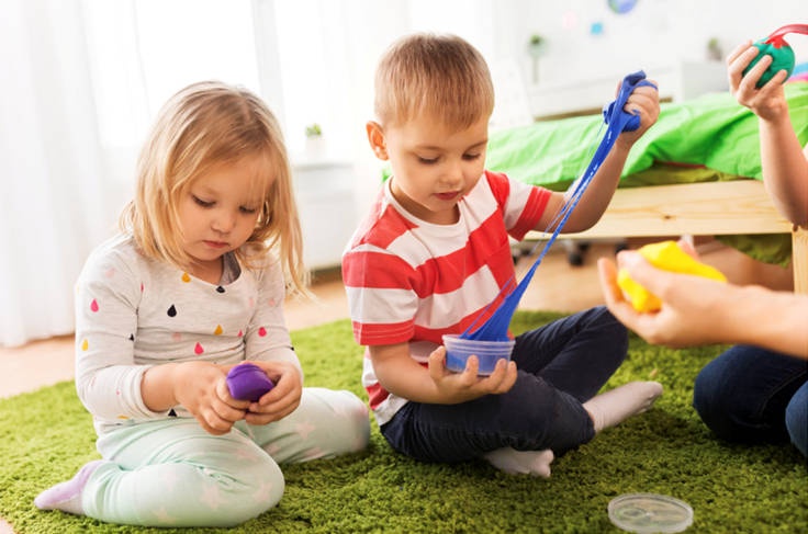 Two children playing with slime on the floor of a nursery or playroom