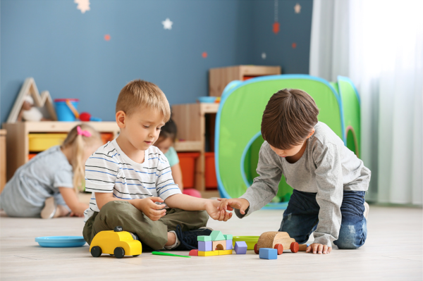 Two children playing on the floor with building blocks