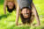 Two children doing handstands on grass in the sun, the image is cropped to only show their top halves