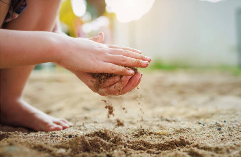 Children's hands playing in regular sand