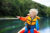 A child wearing a lifejacket sat in a canoe pointing at something out of frame