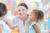 A woman nursery manger playing and smiling with two children in a nursery room.