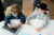 Two children at a desk with a laptop, inspecting phones and a colour chart