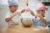 Two children playing with flour in a metal mixing bowl