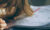 A close up shot of a child's hands writing maths problems in a finely-lined book