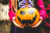 A girls hands holding a pumpkin decorated with black stickers or paper