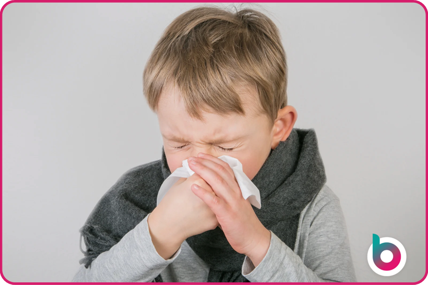 A child sneezing and blowing their nose, indicative of a runny nose