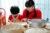 A woman and child making chinese dumplings with a bamboo steamer on the table