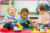 Three children playing with blocks on a soft floor surface