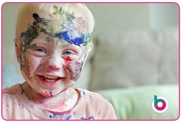 A small child with their face covered in paint
