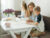 A girl and boy making porridge (or similar) with an adult overseeing
