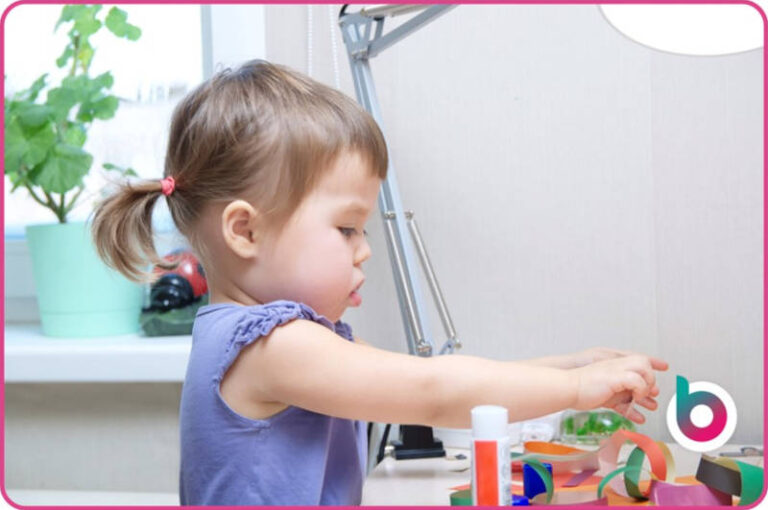 Child playing with paper rings and glue sticks