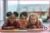 three children lying on the floor looking forwards and smiling behind an open book