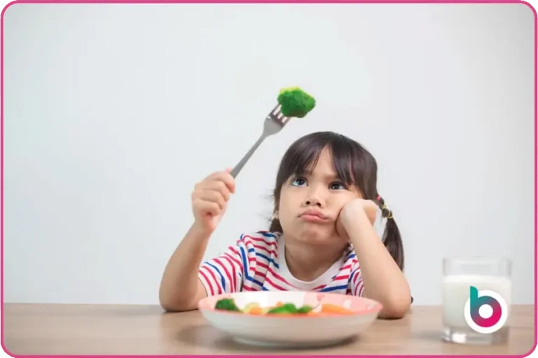 Child with broccoli, looking somewhat disappointed