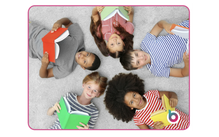 A group of school-aged children lying on the floor reading books